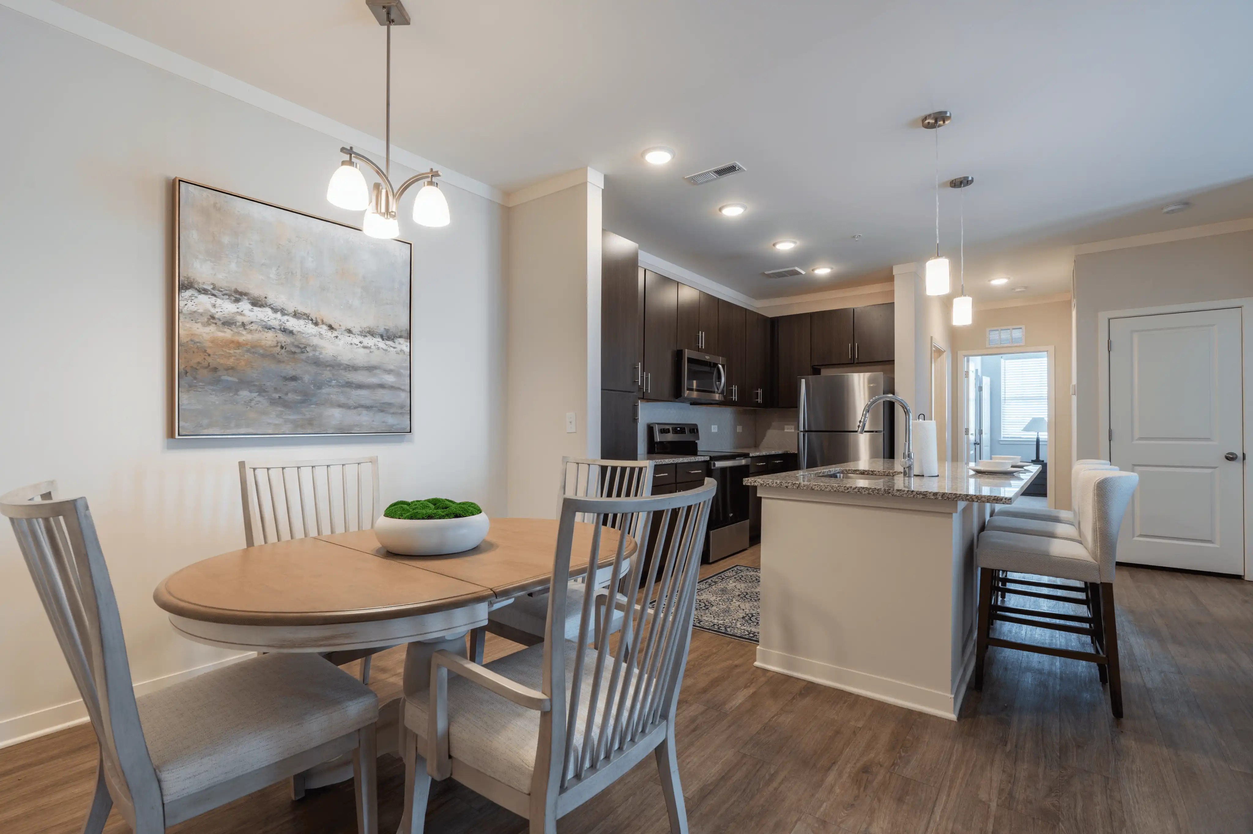 Furnished apartment dining area and kitchen with a round table, kitchen island, and bar stools at The Reserve at Cool Springs, Elizabethtown, KY