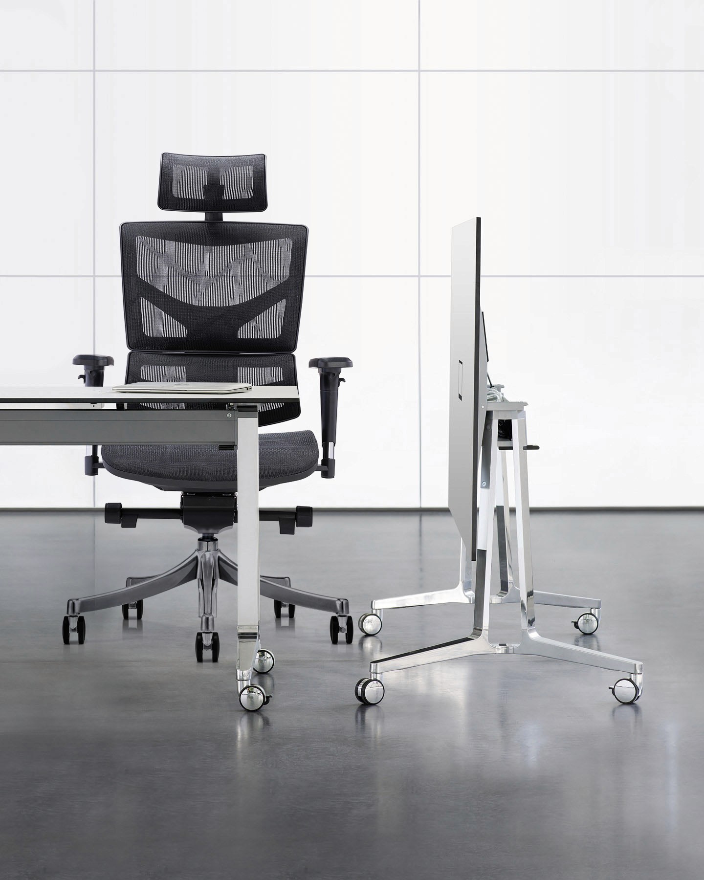 Modern office setup featuring a black mesh ergonomic chair paired with a minimalist white desk and polished metal furniture