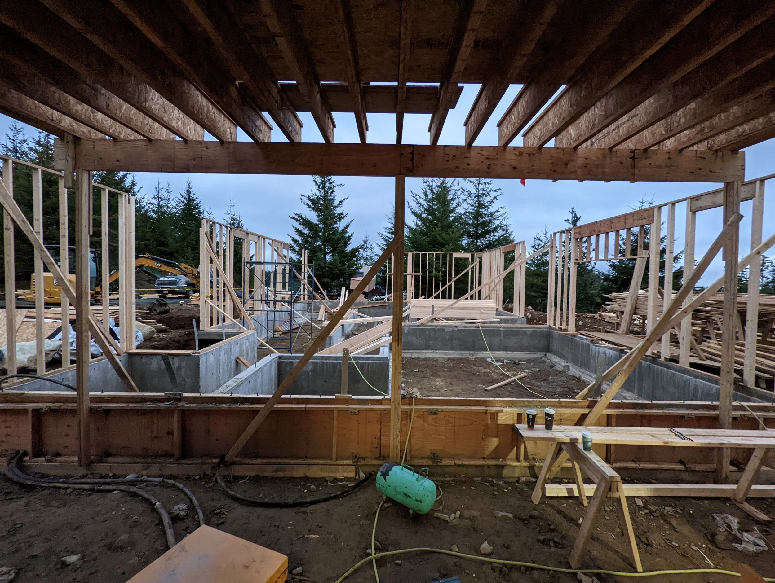 Modern two-story home with large glass windows, warmly lit interiors, and a balcony. Surrounded by trees and a manicured lawn at dusk. Cozy ambiance.