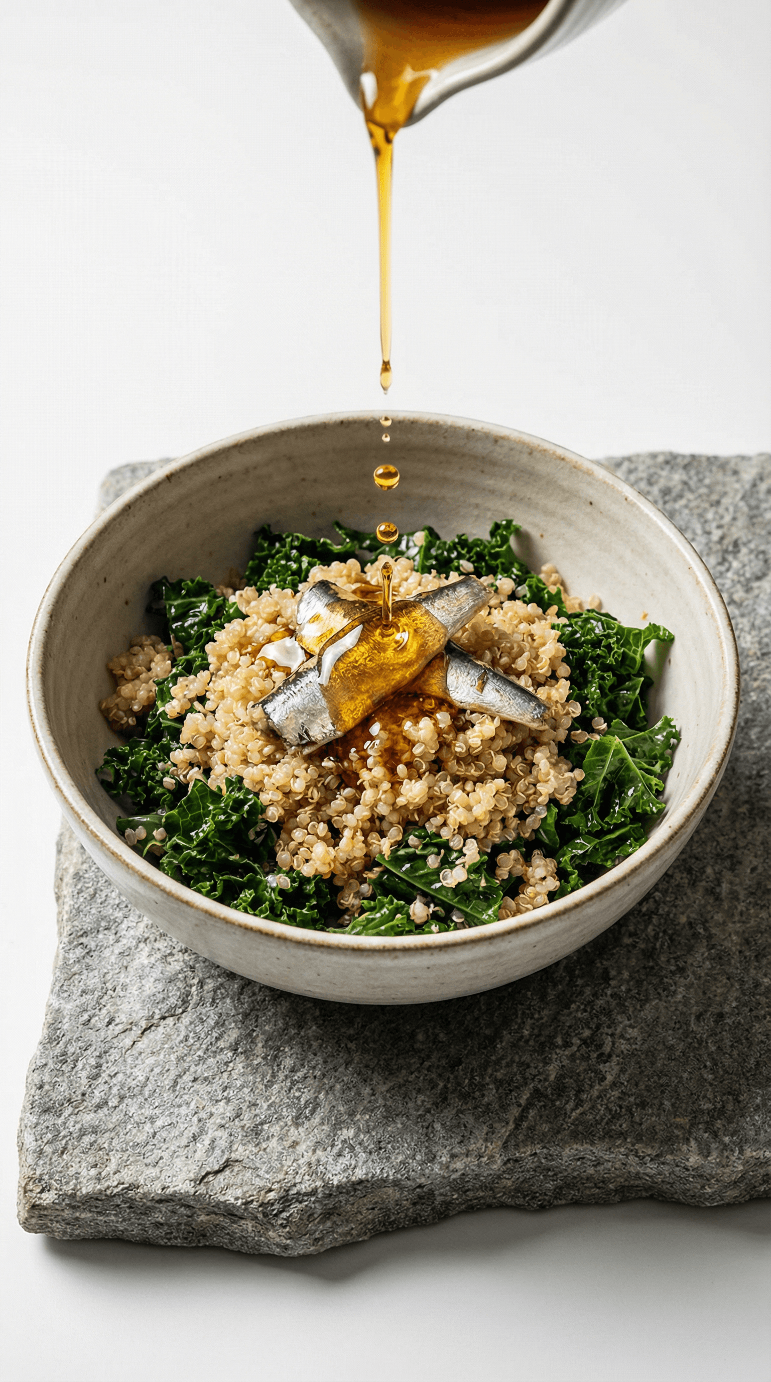 Close-up bowl of quinoa and greens with fish and oil drizzle captured mid-pour