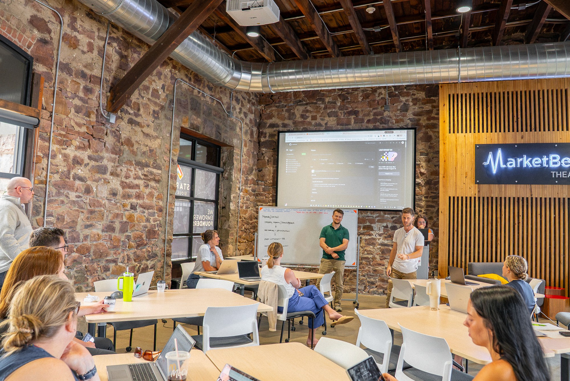 Three colleagues talking through their work together in an open-plan office
