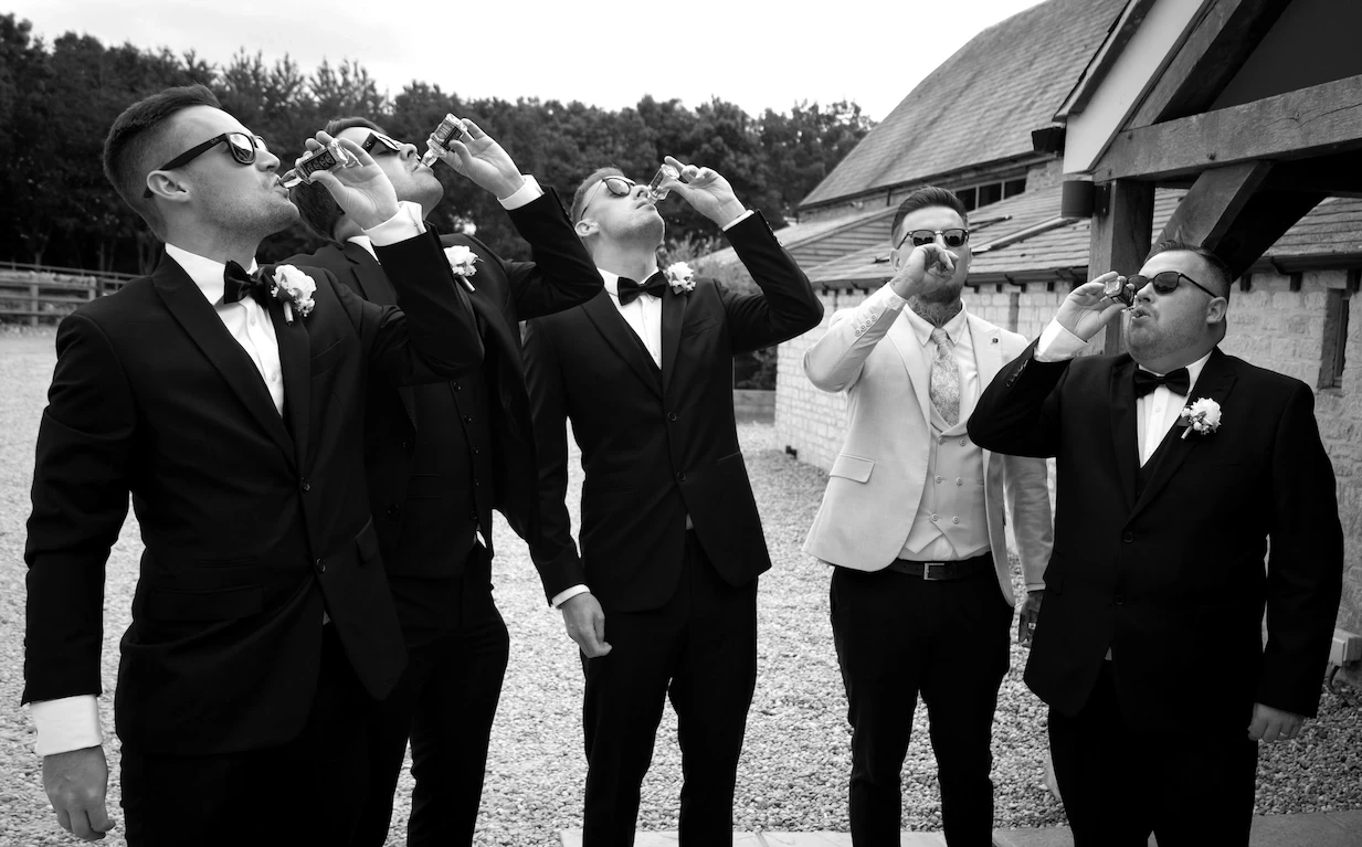 Groomsmen taking celebratory shots outside at a Shropshire wedding venue