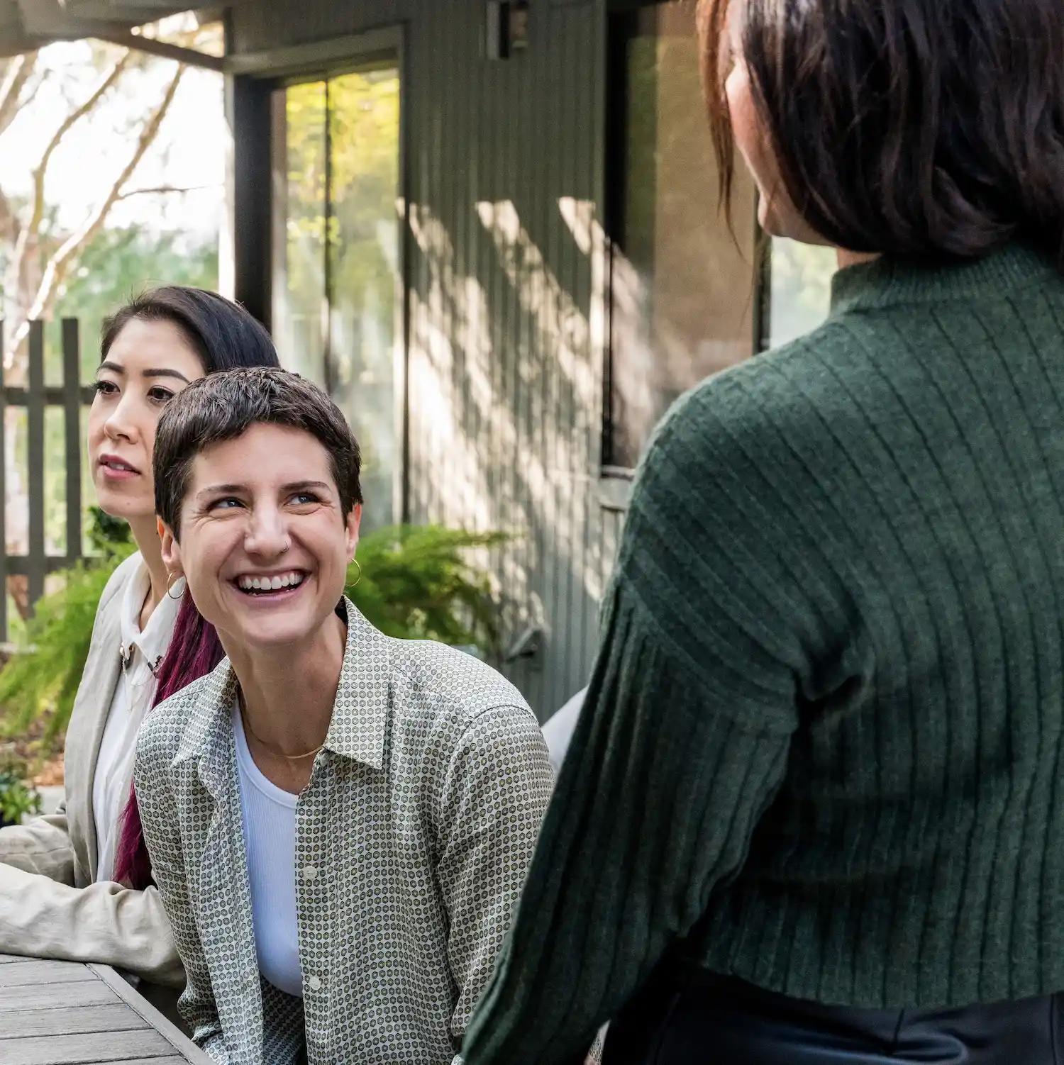 Group of people smiling and engaging in a supportive discussion outdoors, representing affirming gender exploration therapy in Los Angeles.