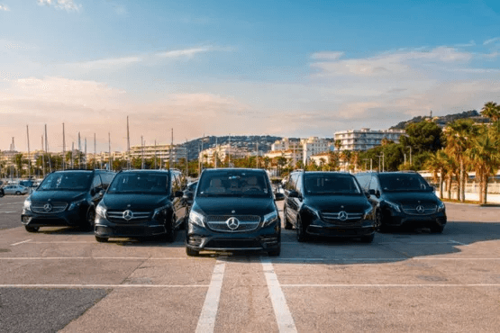 A man in a suit standing next to a black car