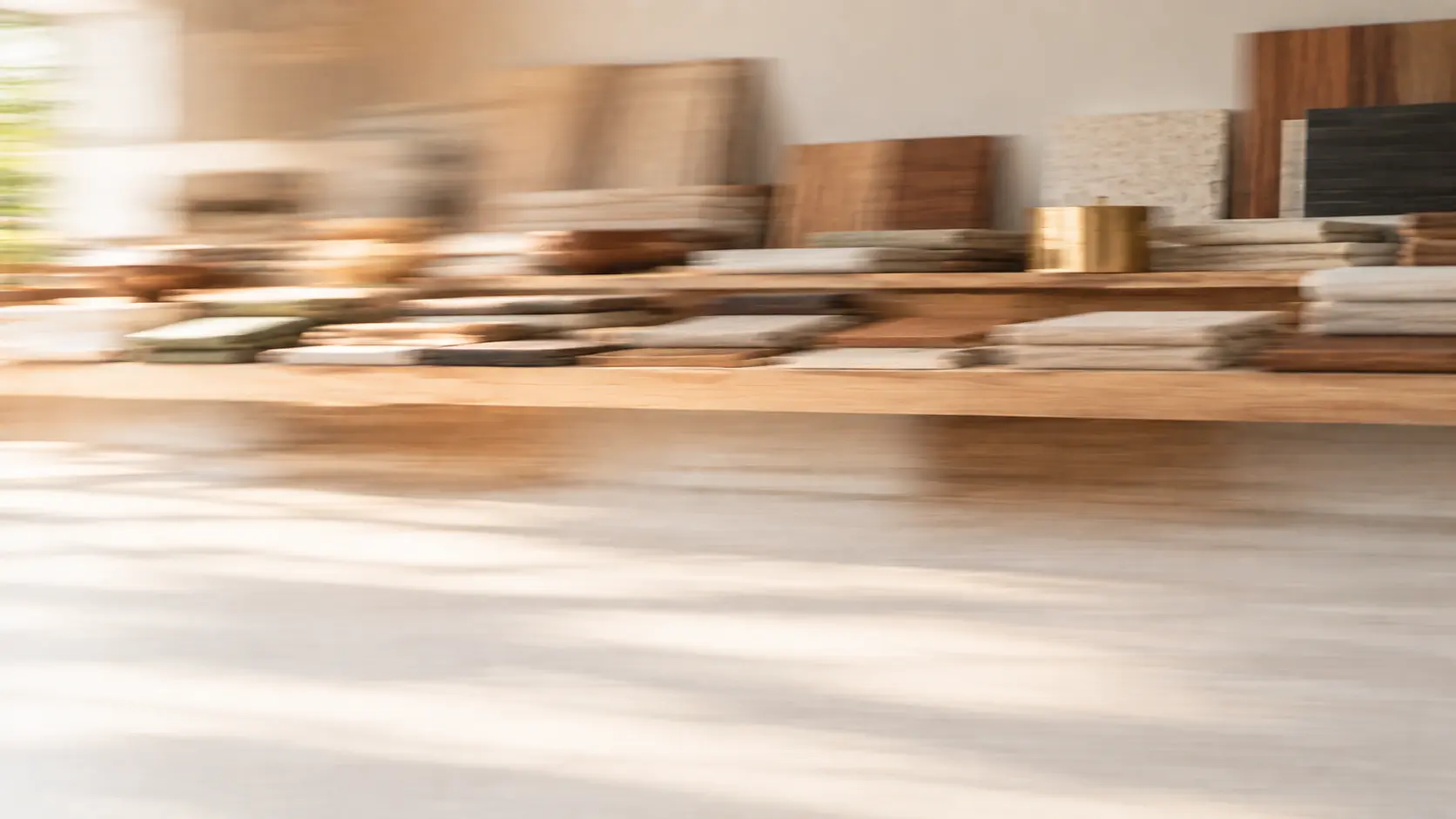 Workbench with drawings, wood samples and a brass detail, softly blurred by motion
