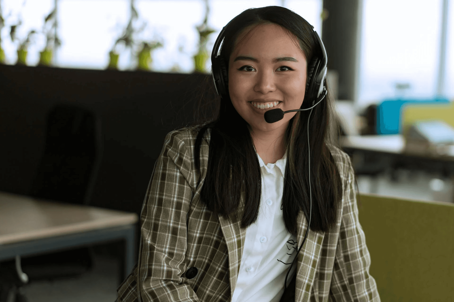 A person smiling while holding a microphone indoors.