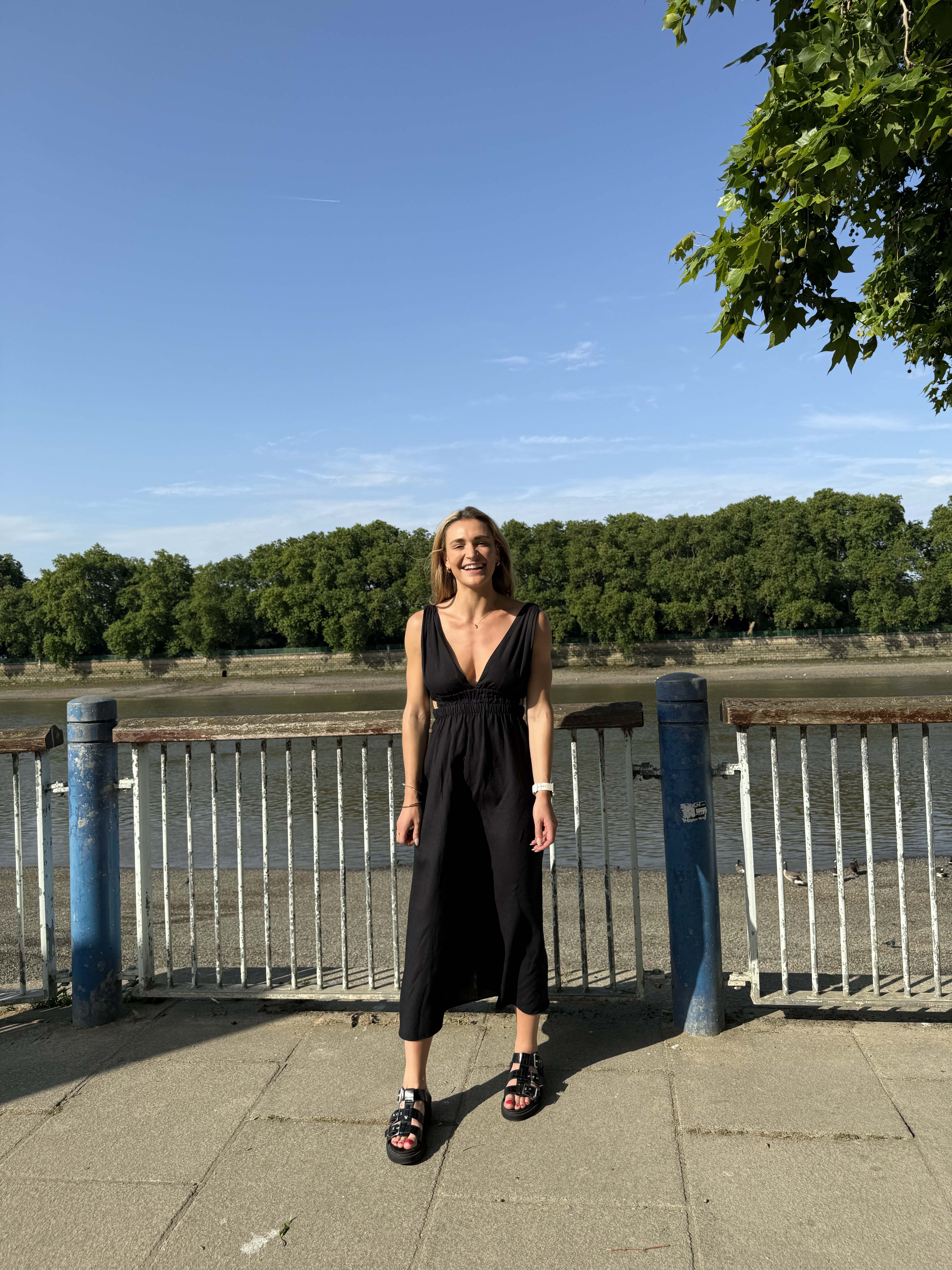 A winding road cuts through rocky terrain, surrounded by patches of green grass and illuminated by sunlight.