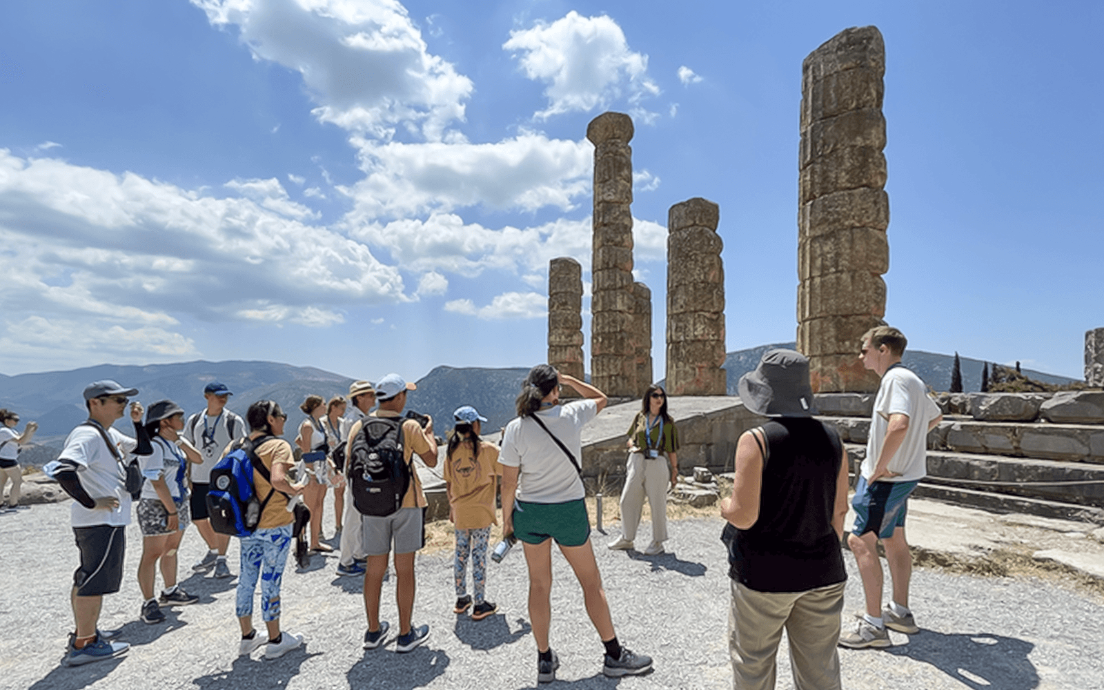 游客们在希腊德尔斐游览古代遗址,导游正在解释其历史意义。