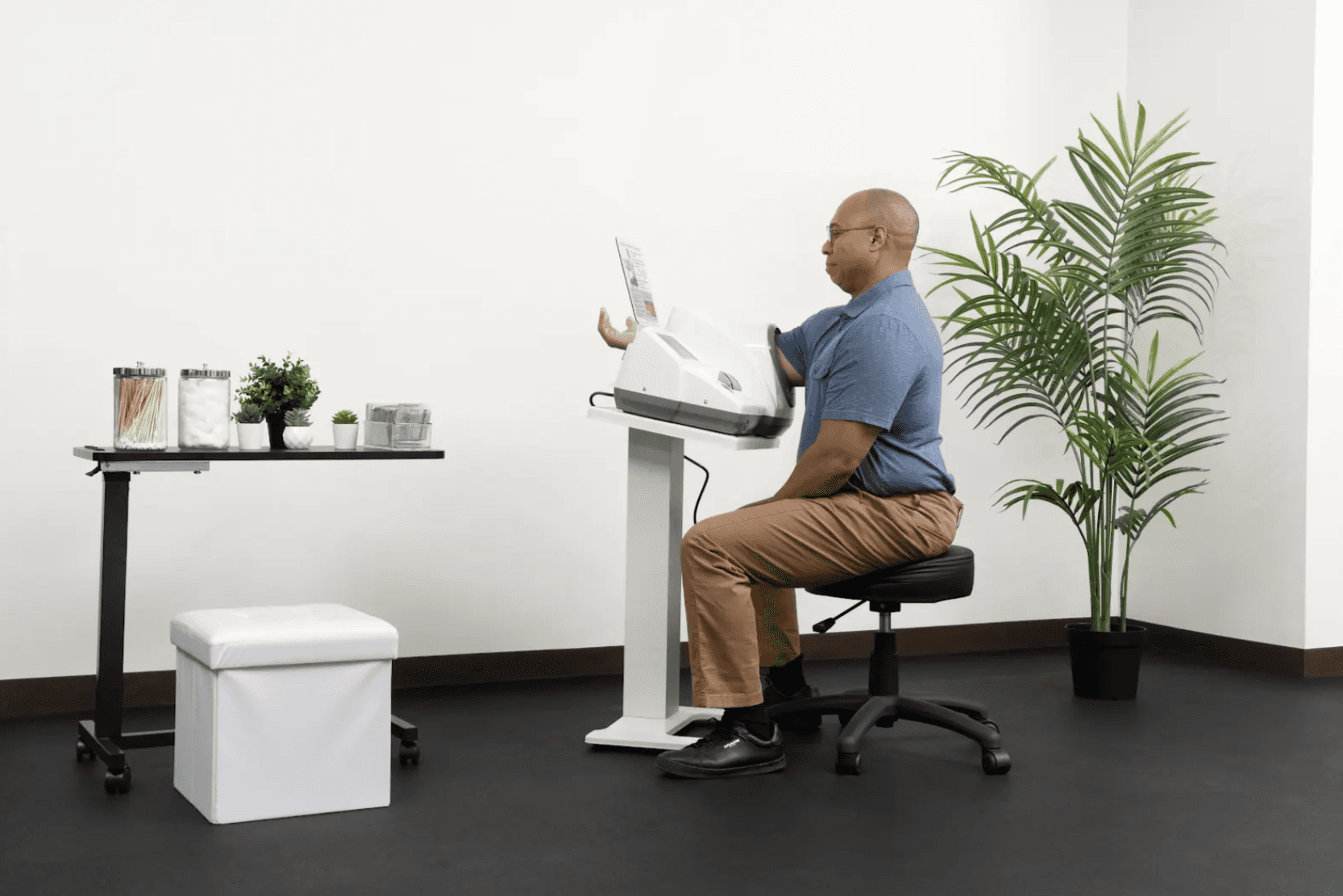 A man sitting on a stool and checking his health results on an InBody professional blood pressure monitor in a medical office setting.