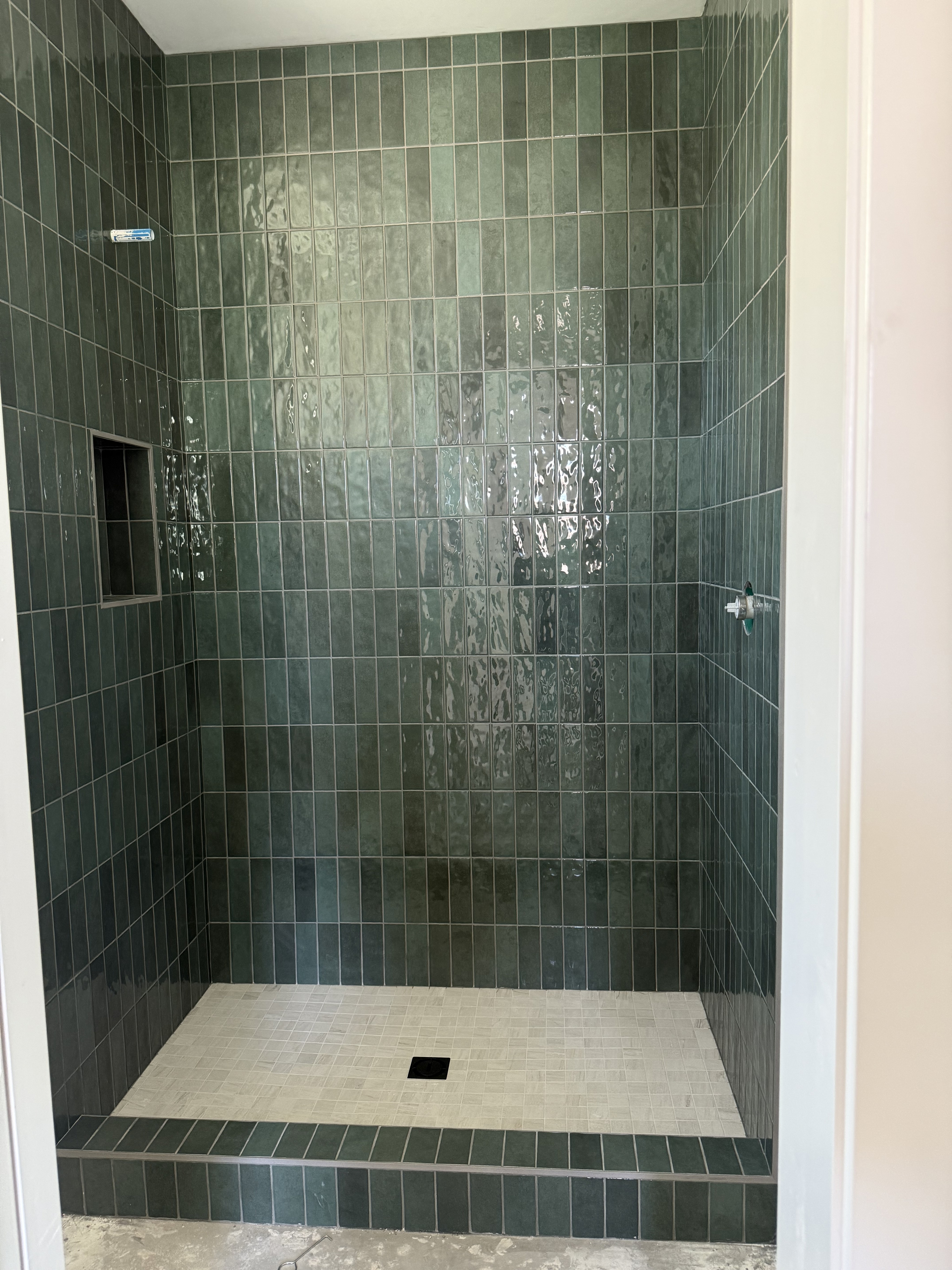 Luxurious bathroom vanity area with a dramatic wall featuring large format natural stone tiles in varying earthy tones and complex veining, serving as a striking backsplash above a double sink vanity.