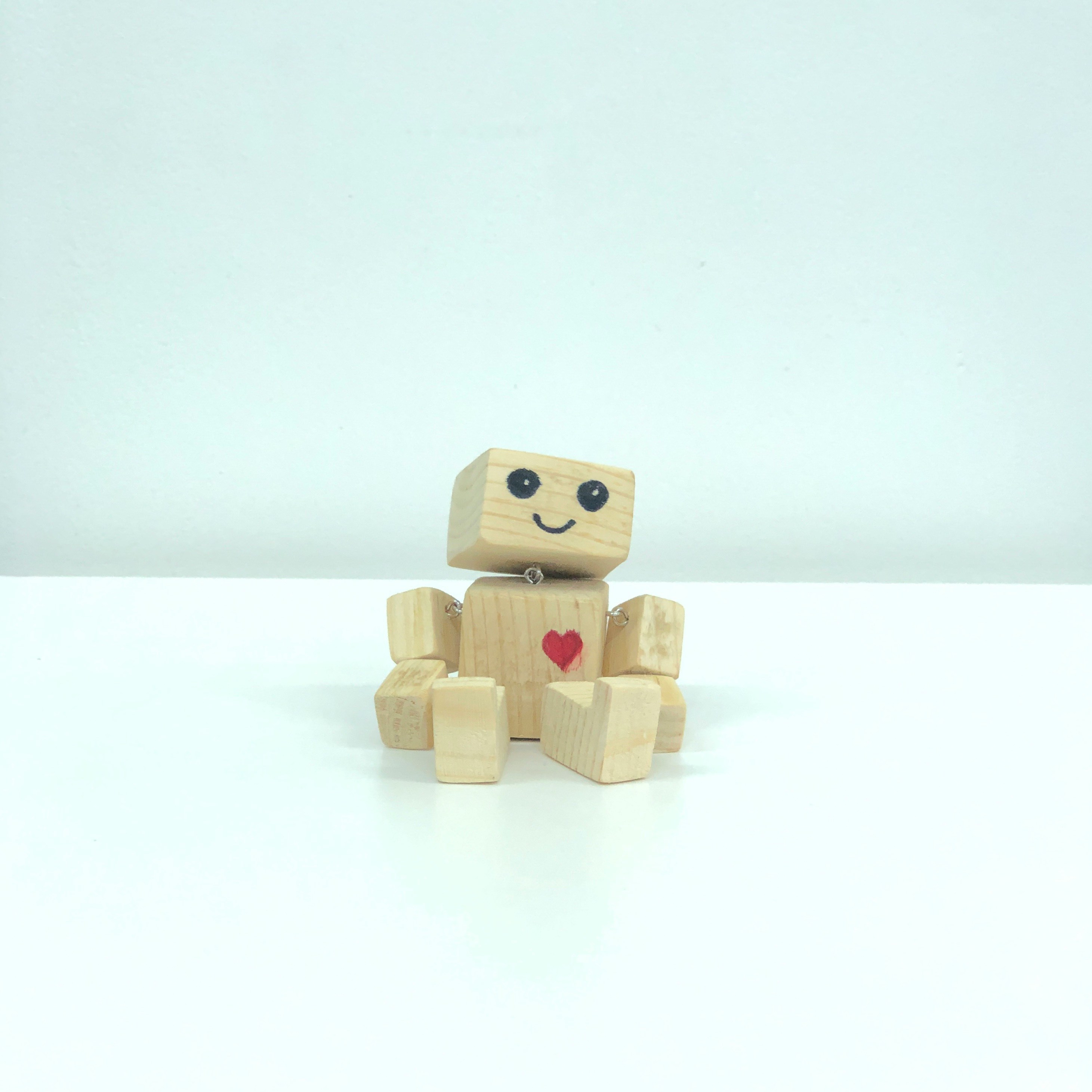 brown wooden robot toy on white surface