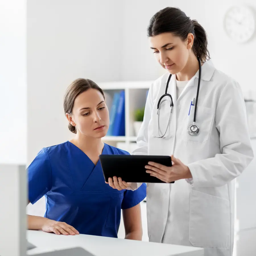 AI transcription in healthcare assists a doctor and nurse as they review patient records on a digital tablet in a medical office