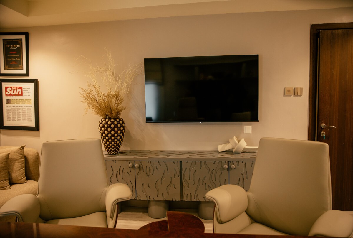 A modern kitchen and living room with white cabinets, herringbone floors, and a gray sectional sofa.