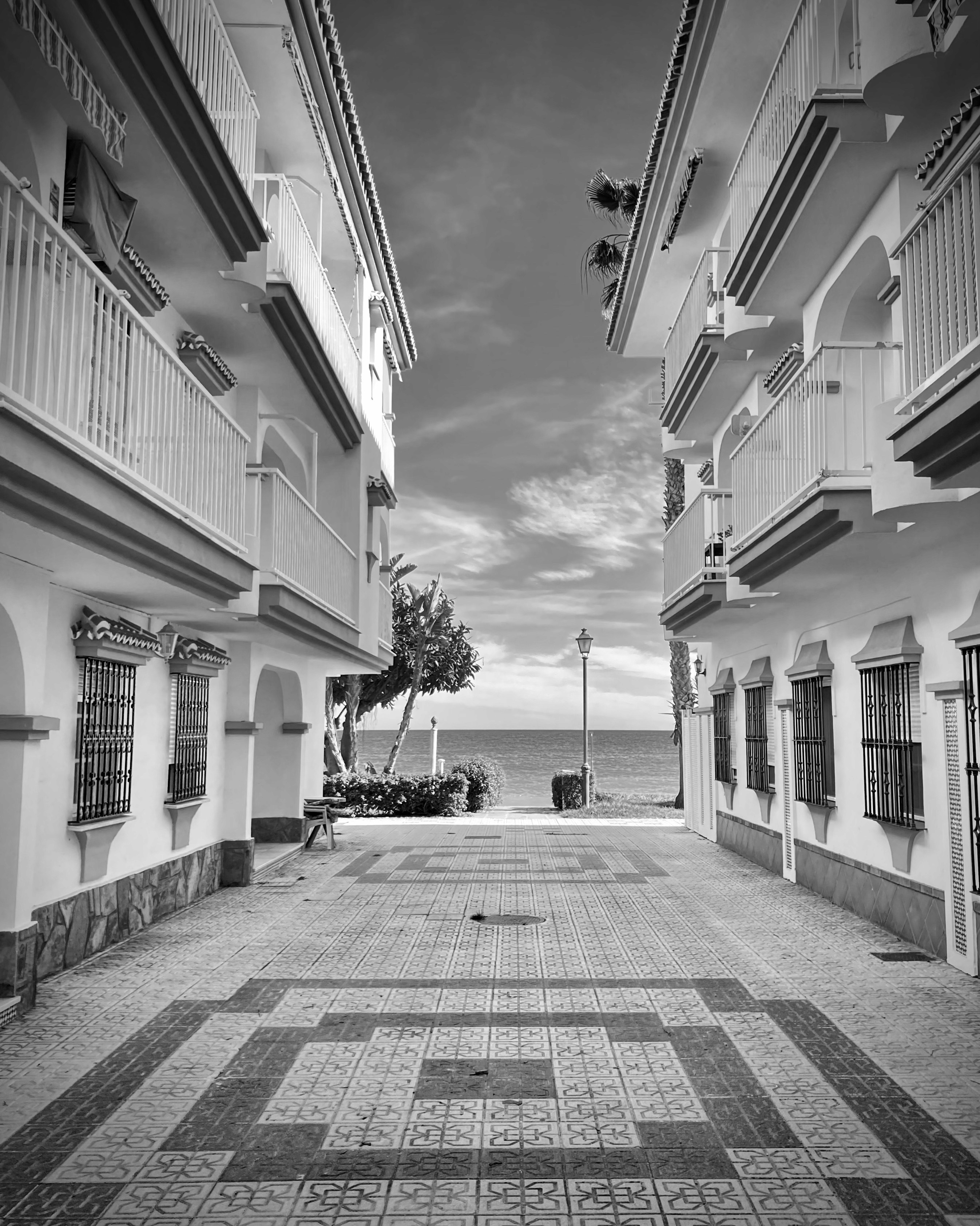 Symmetrical artistic photo, with Spanish apartment blocks on both sides and a view of the sea in the distance.