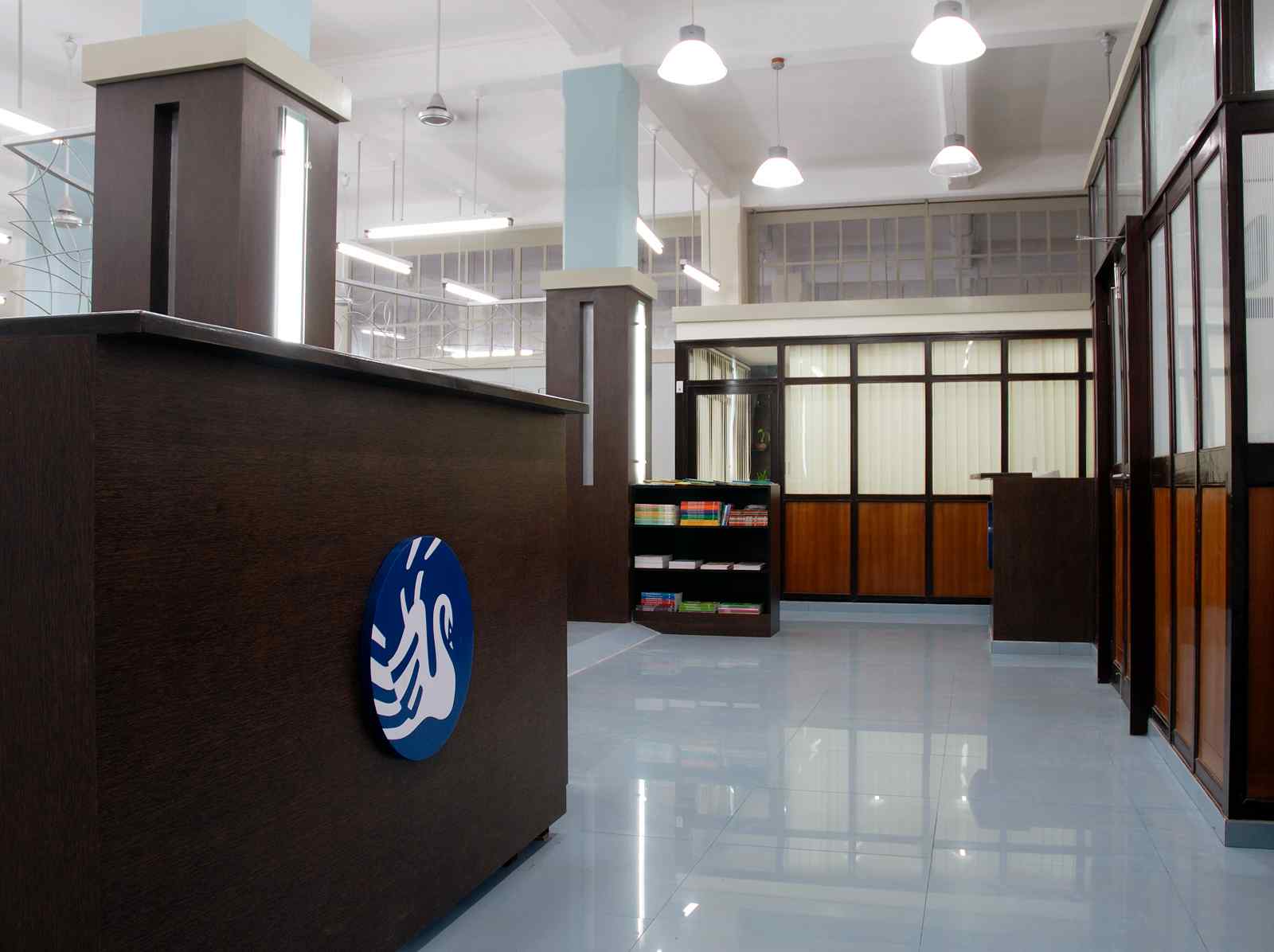 Nature-inspired preschool entrance with sculptural tree partitions and suspended green leaf ceiling panels.