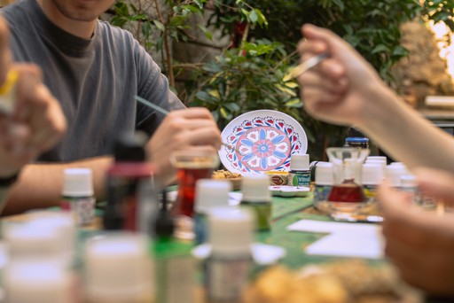 Participants engaged in a Turkish tile painting workshop in Istanbul, surrounded by paint jars and an intricately designed ceramic plate. This workshop offers a unique opportunity to explore Turkish ceramic art in a creative setting.