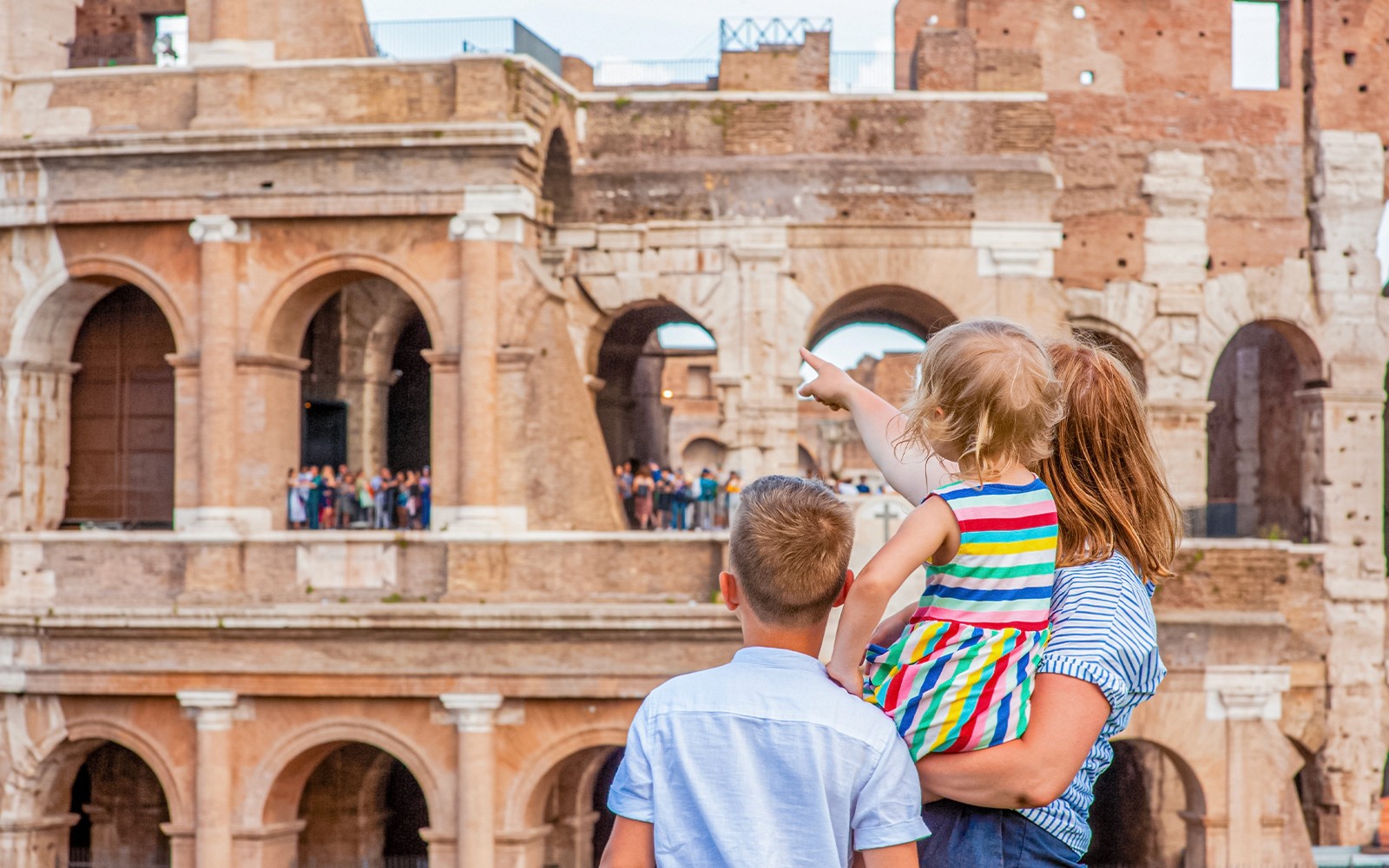 家庭在意大利罗马探索斗兽场，孩子们观察古代建筑。