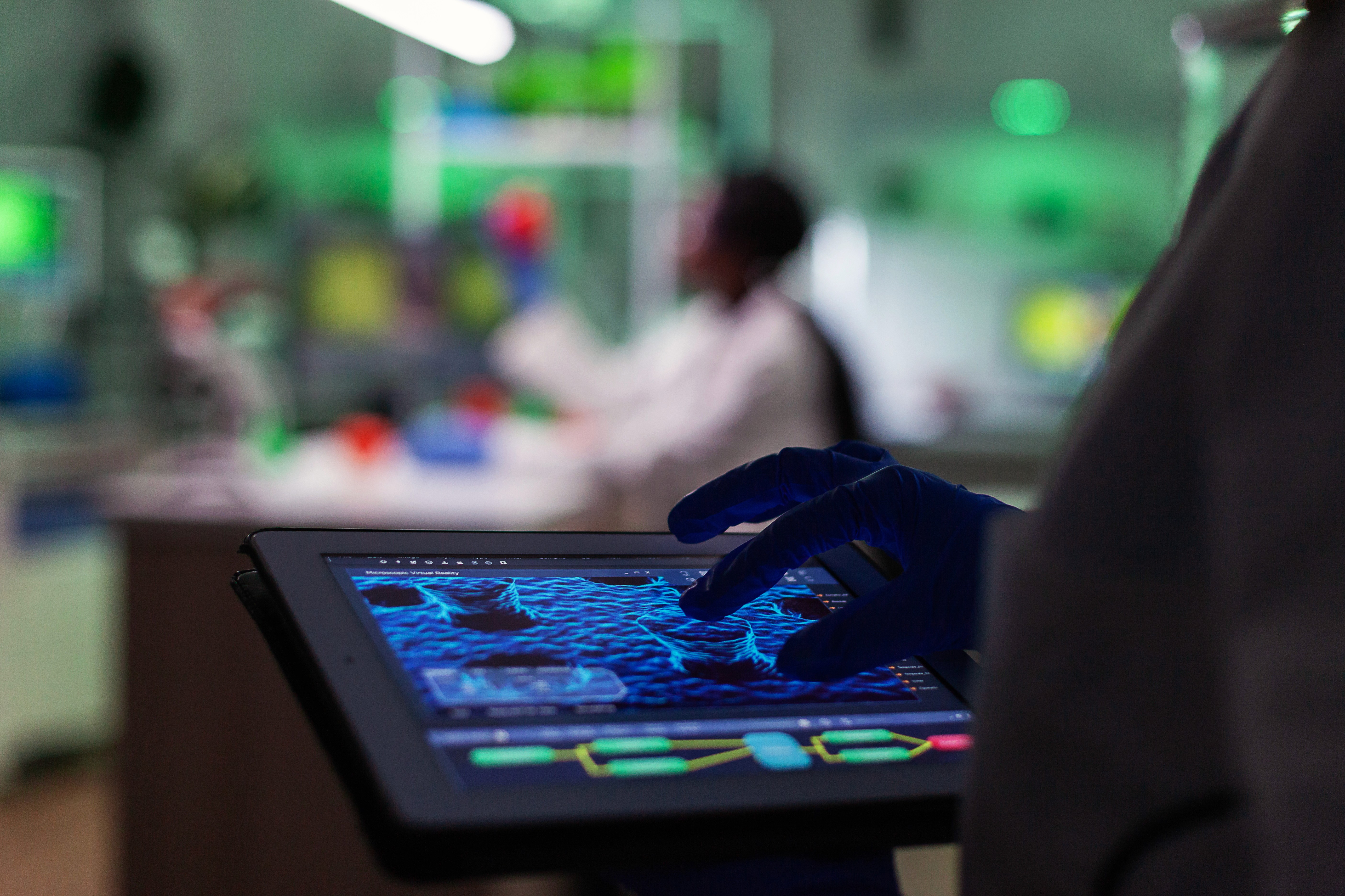 Close-up of a scientist holding a tray of petri dishes with purple cultures, wearing gloves and safety gear.