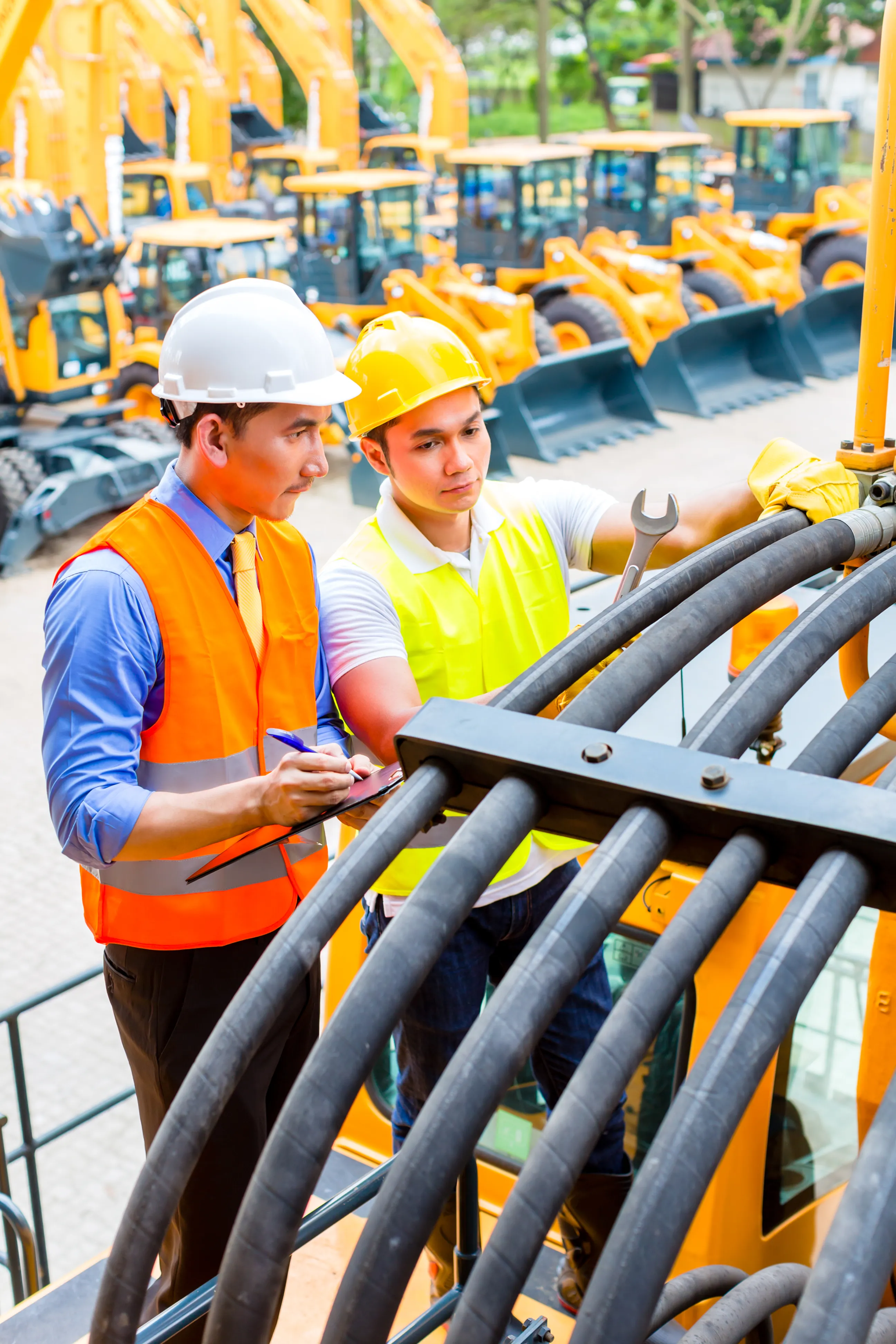 Construction site engineer wearing a safety vest and hardhat looking at structural blueprints.