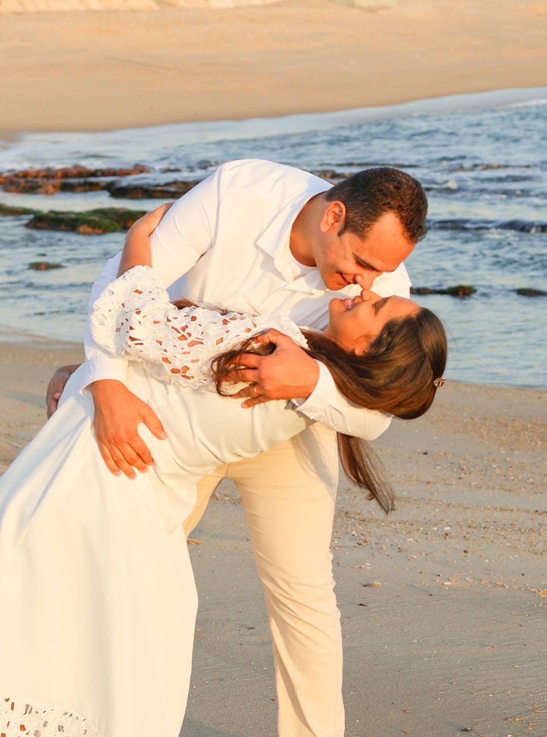 A bride and groom share a kiss surrounded by a joyful bridal party.