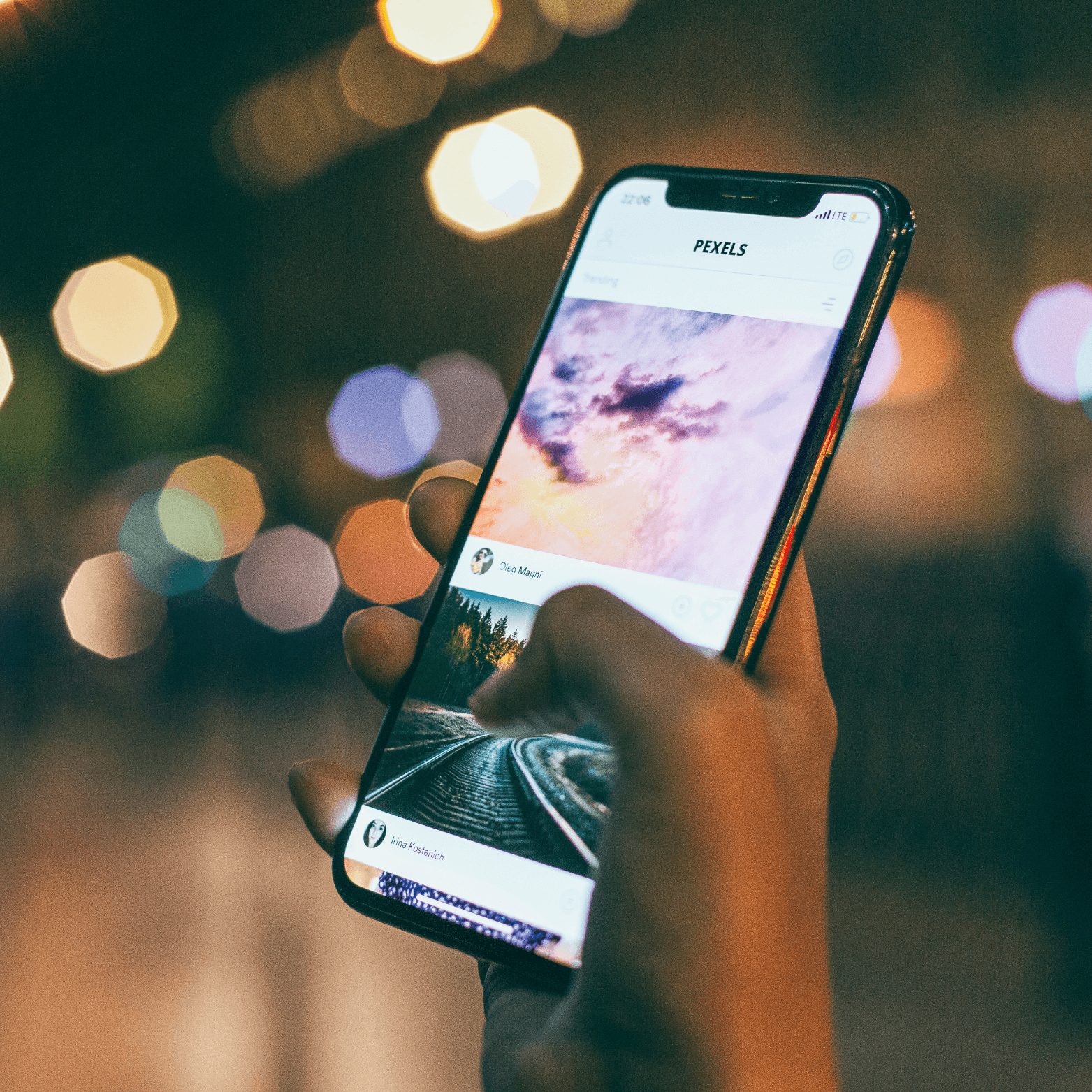 An image of a hand holding an Iphone in the nightwhile using Instagram