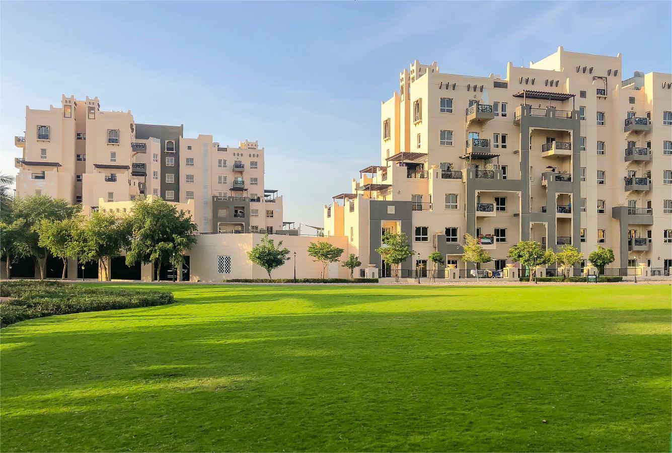 Family-friendly park with shaded play area in Remraam Dubai, surrounded by greenery and residential buildings.