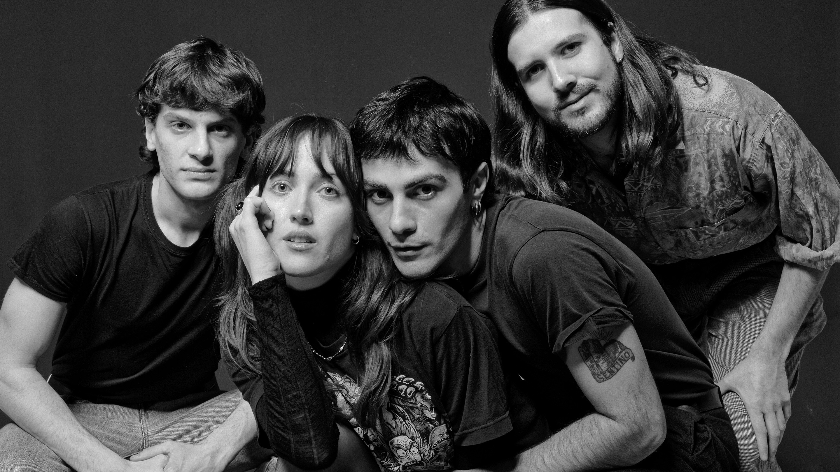 Four people crouching on the floor looking into the camera