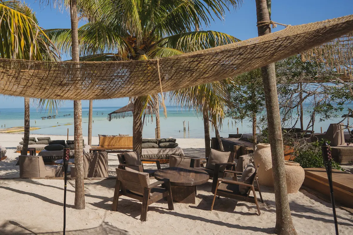 Vista panorámica del club de playa frente al mar en Nomade Holbox en Holbox, México, con cómodos camastros y un ambiente relajante