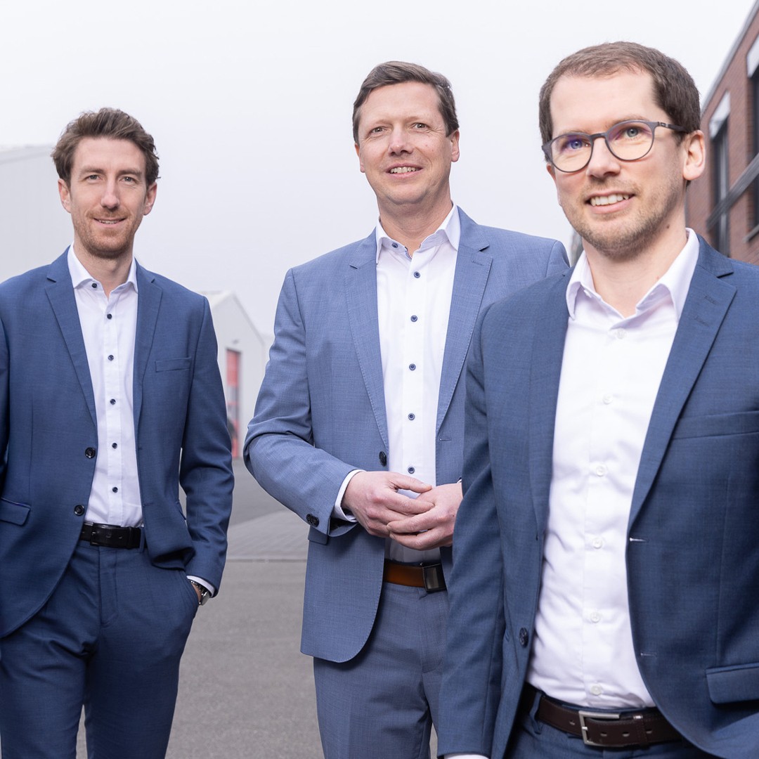 Geschäftsteam in Anzügen: Drei lächelnde Männer im Freien. Experten, Führungskräfte.