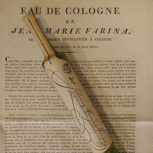 Sebotol vintage eau de cologne yang dibungkus dalam kertas, bersama dengan dokumen cetak berbahasa Prancis yang merinci "Jean Marie Farina."