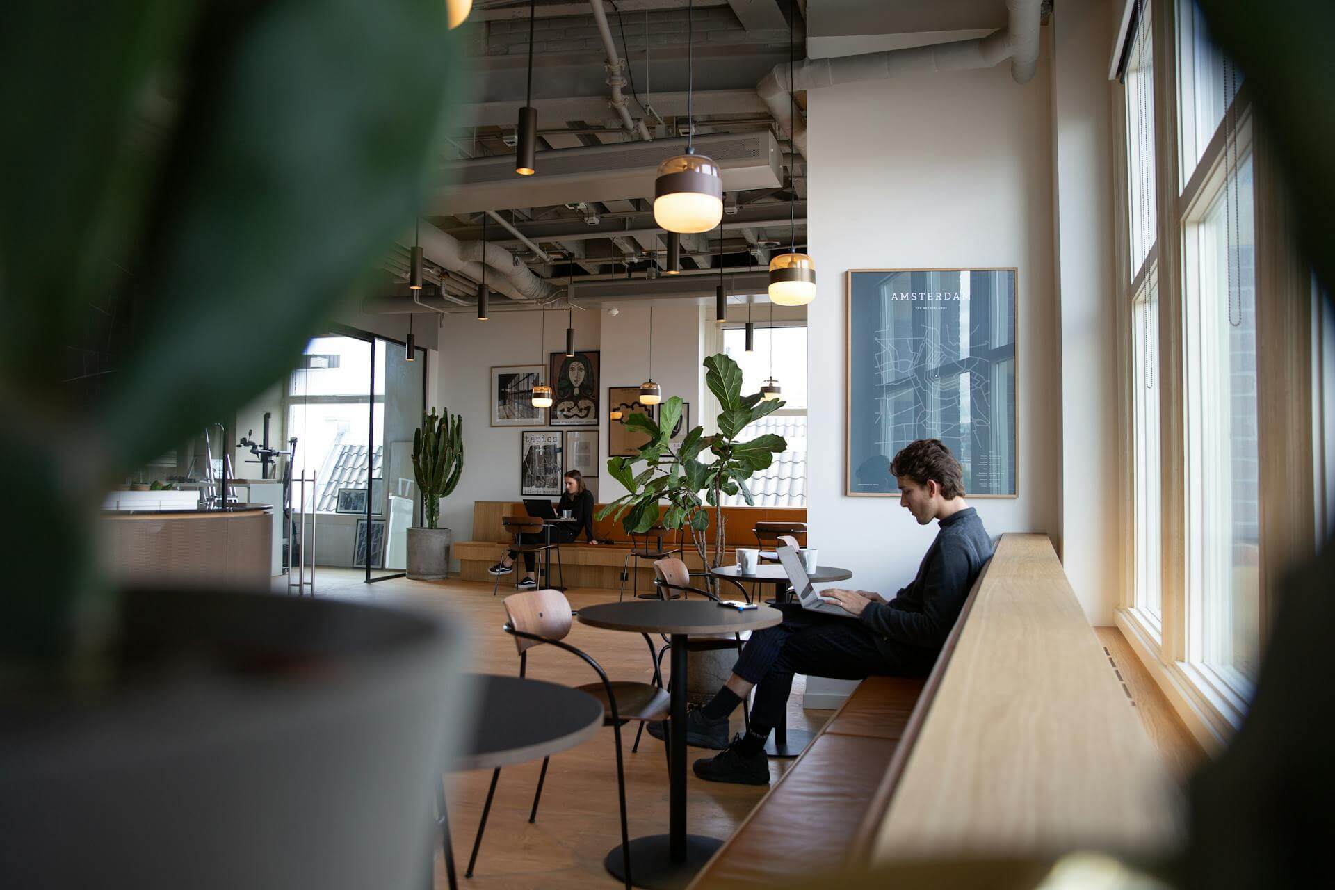 A person in office sitting on a bench and using a laptop