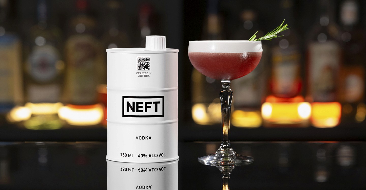 A NEFT Barrel and a glass of Pomegranate Cape Cod on a bar counter.