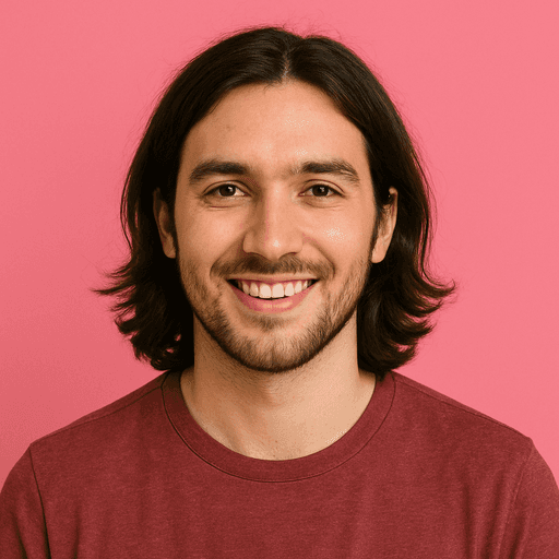 A smiling man with long hair and a beard in a maroon shirt stands against a pink background, conveying a warm and friendly tone.