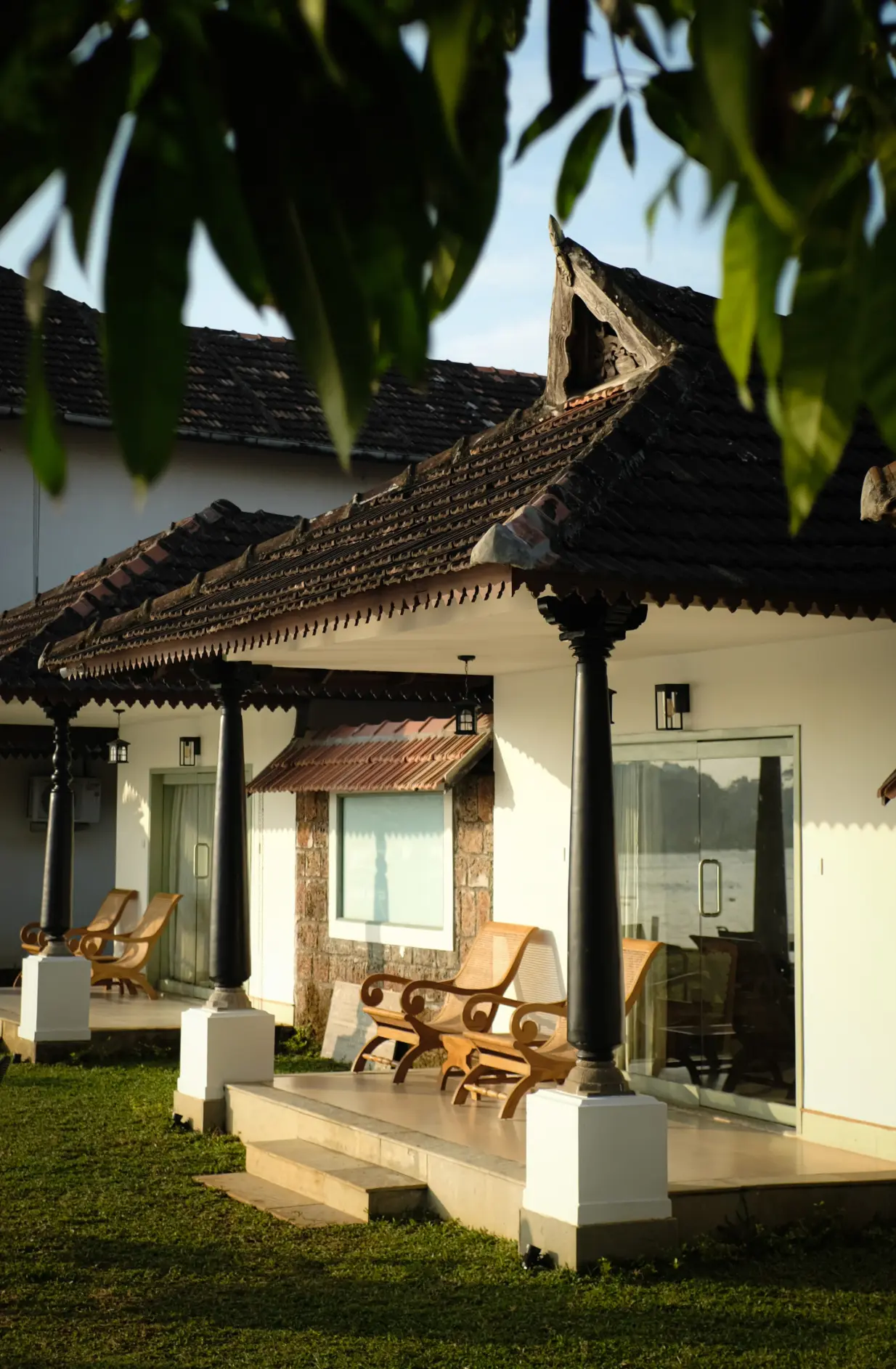 Guest veranda at Vedic Village Alleppey with wooden lounge chairs and carved pillars for family and friends to gather
