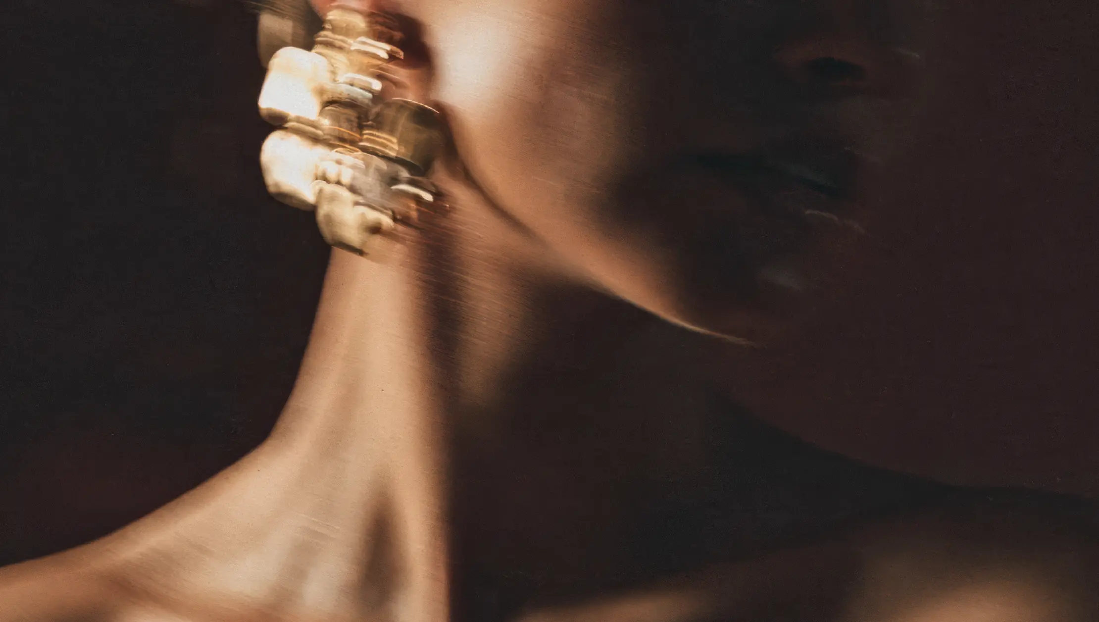 Close-up of a person wearing gold jewelry against a dark background