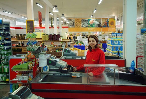 Cassa supermercato con addetta al registratore: retail, pagamenti e customer service