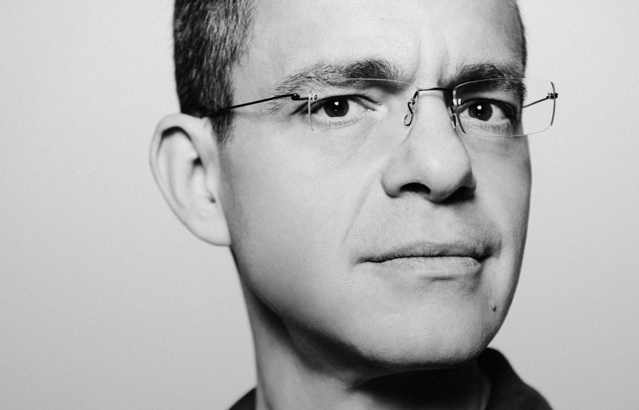 A glass planthouse from the outside in an expansive empty desert at dawn.