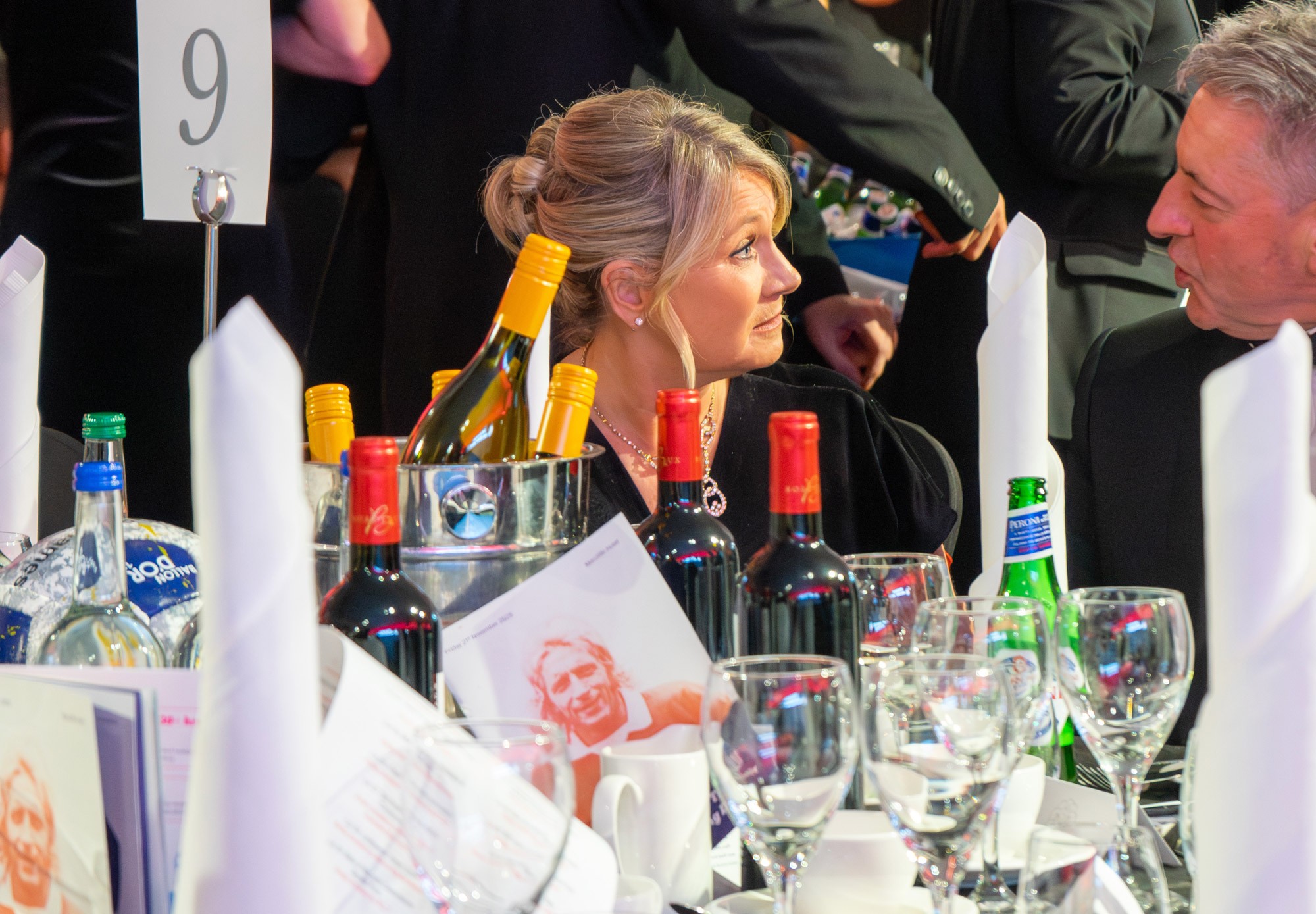 woman at a dinner table listening to another guest