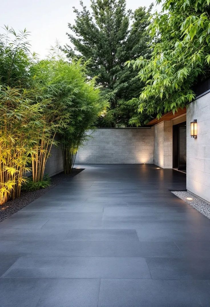 تصميم ممر خارجي واسع يبرز فخامة استخدام حجر البازلت المجلي ذو اللمعة الناعمة، مع تنسيق حدائق يدمج الإضاءة الدافئة والألوان الداكنة لإبراز جماليات التصميم المودرن.