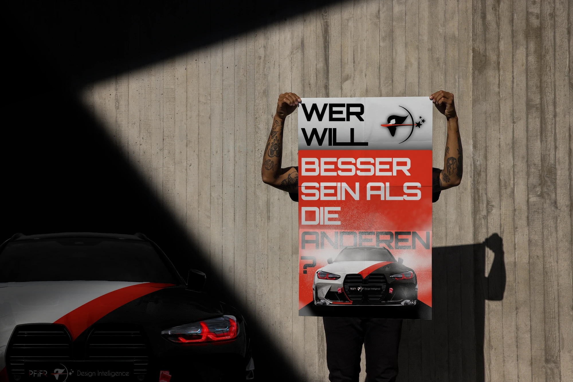 Person holding a bold red and white poster with high-performance car visual, symbolizing ambition, identity and strong brand messaging by PFiFR Design Intelligence.