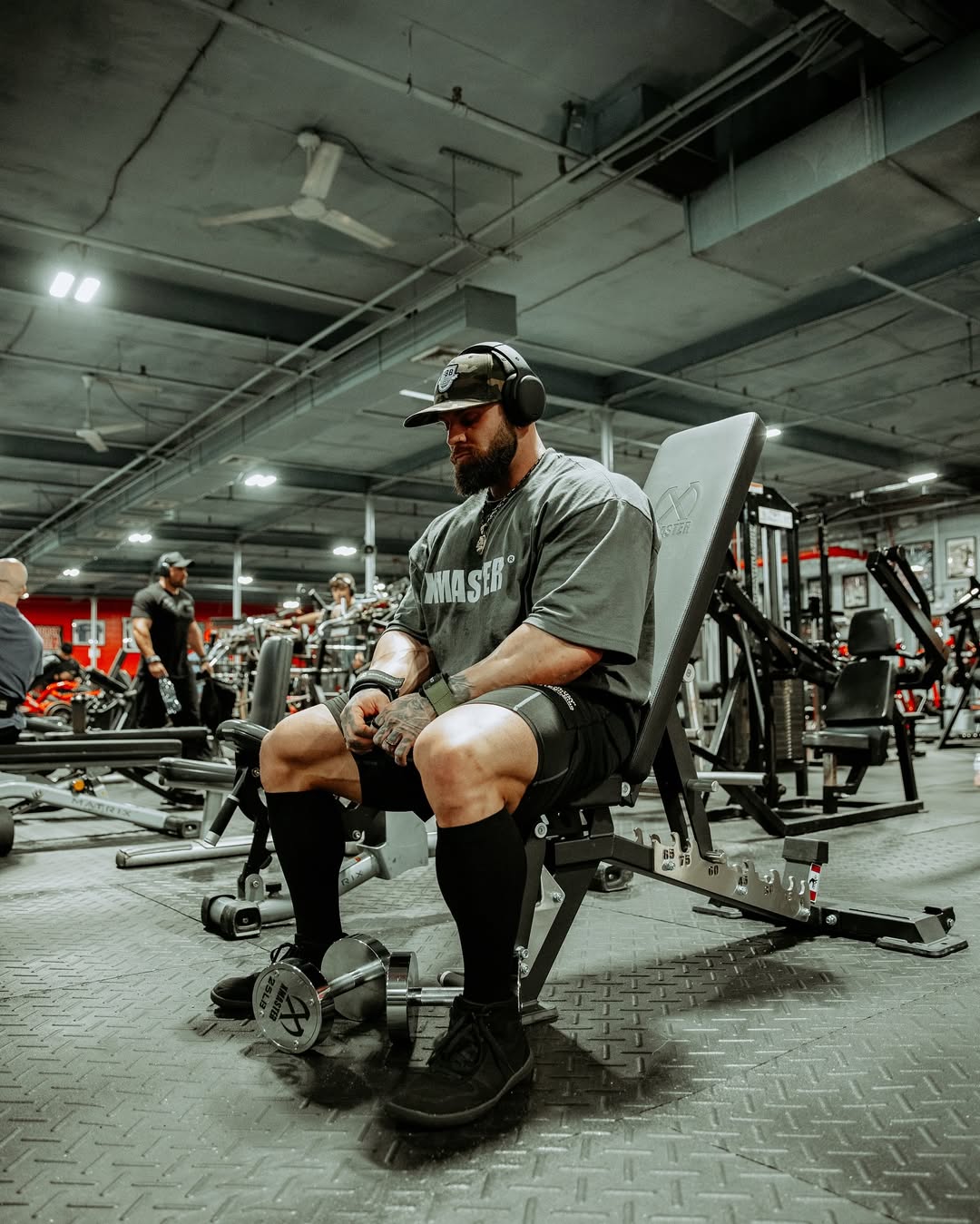 Two individuals are working out in a gym, focusing on dumbbells and strength training equipment.
