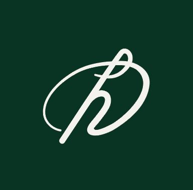 Blonde woman in a black long-sleeve and apron, arms crossed—minimalist studio portrait on a beige background.