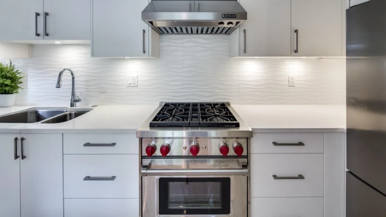 Professional-grade kitchen with 6-burner gas range, white wave-pattern backsplash, quartz countertops, and modern grey cabinetry