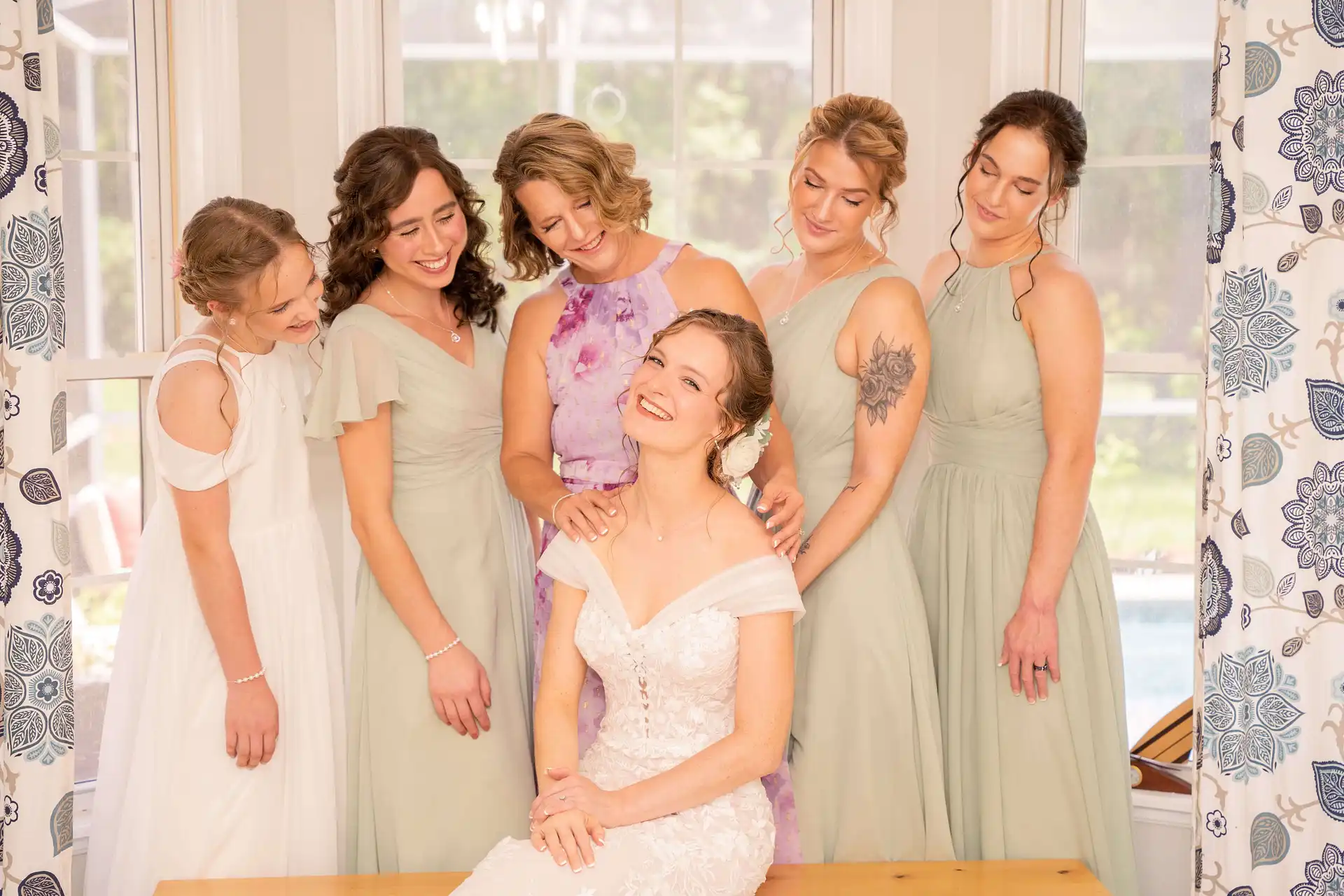 A bride with her bridesmaids and mother gently looking at her from over her shoulder