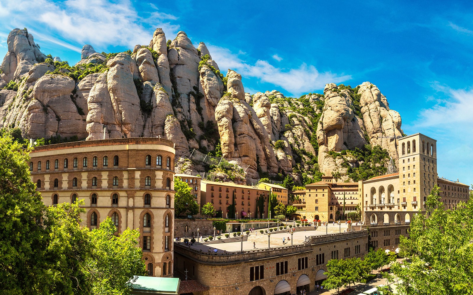 Montserrat kolostor sziklás hegyi háttérrel, kék ég alatt.