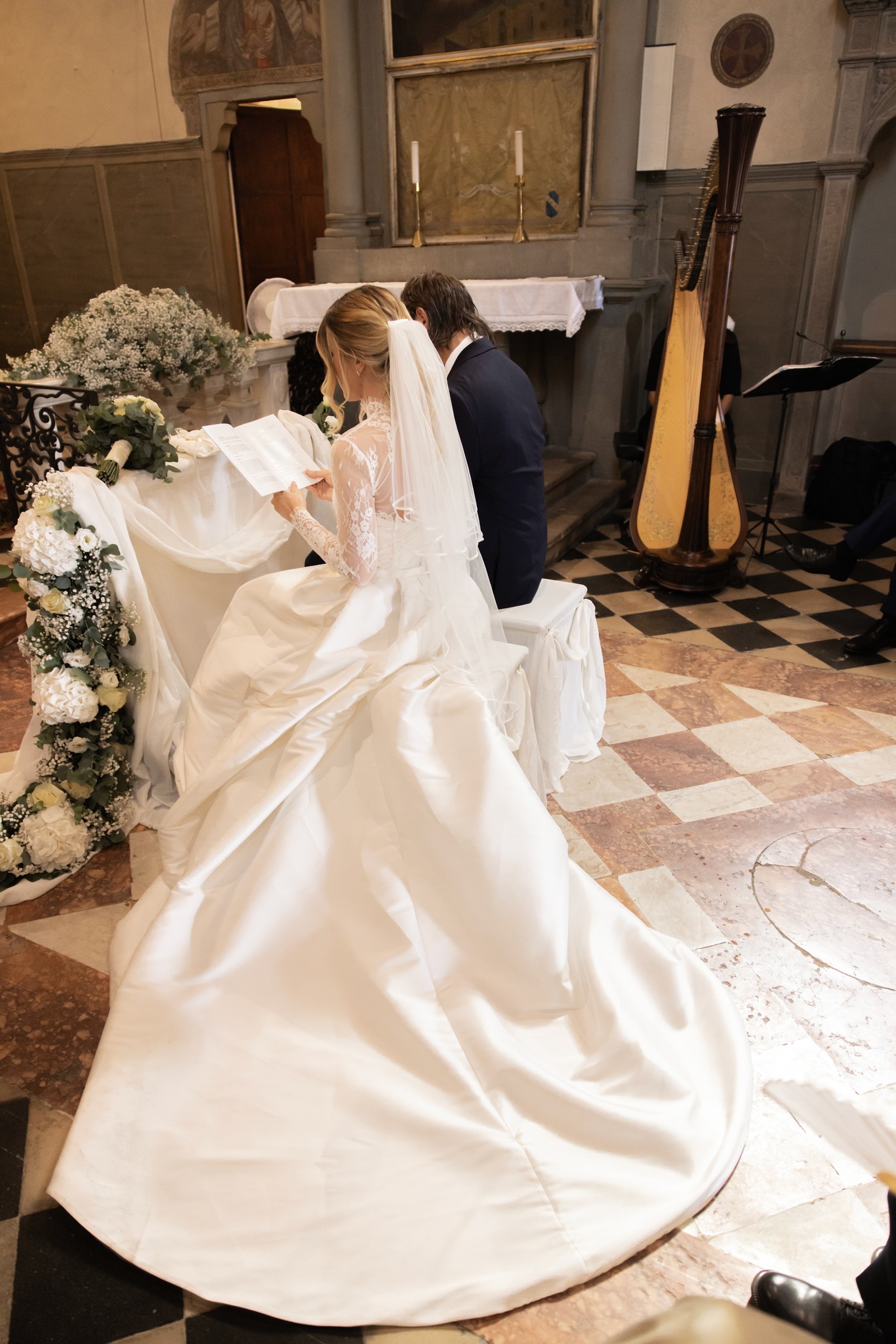 Sposa in abito bianco con strascico abbraccia lo sposo in Chiesa a Bolgheri durante la cerimonia nuziale