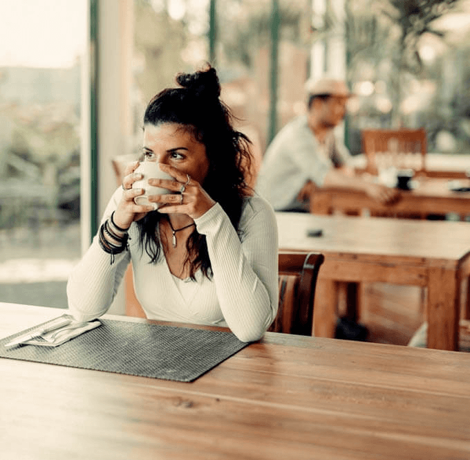 Woman drinking from a mug at a table