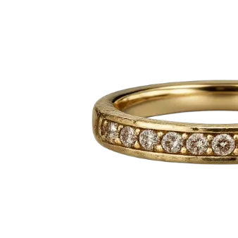 A gold diamond eternity ring with a row of sparkling round-cut diamonds set along a polished band, showcasing luxury jewelry craftsmanship.