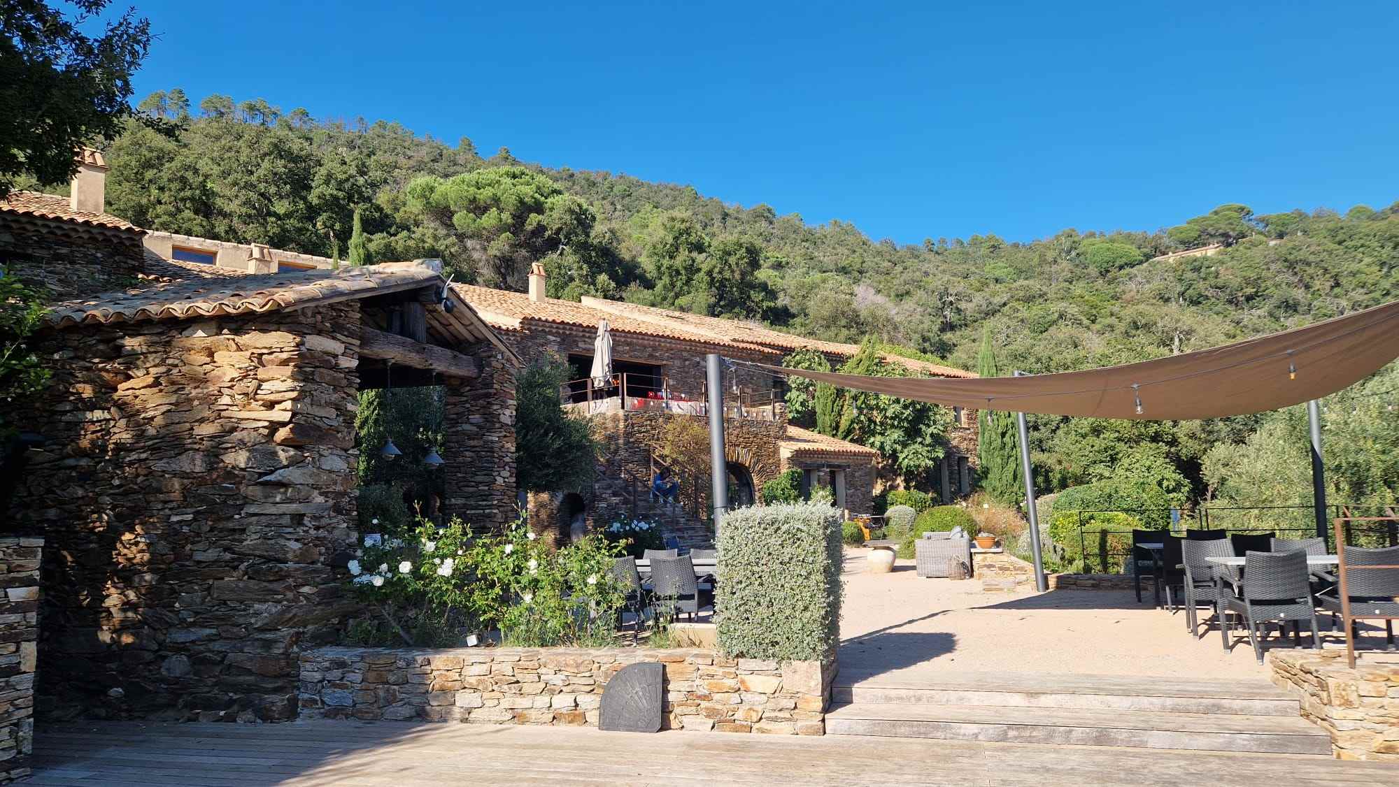 Rustic stone villa exterior with wooden deck and garden at Ulu Yoga luxury retreat center in nature.