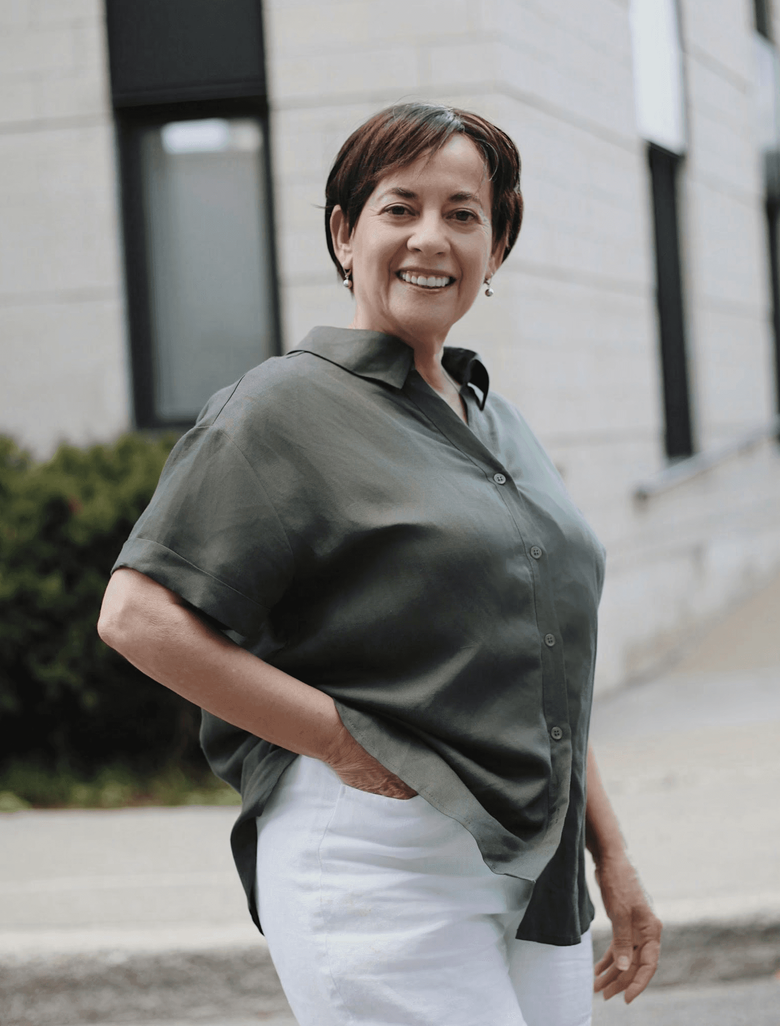 man in green button up t-shirt and white pants standing on road during daytime